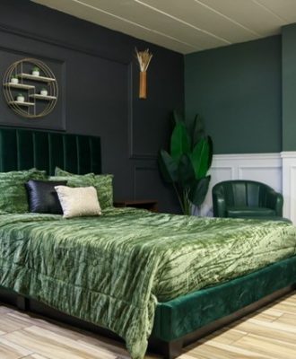 hotel room with green bed spread and multi color walls.
